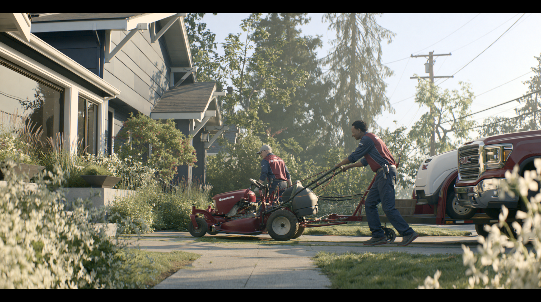 A lawn-care team unloading equipment beside a neighborhood home